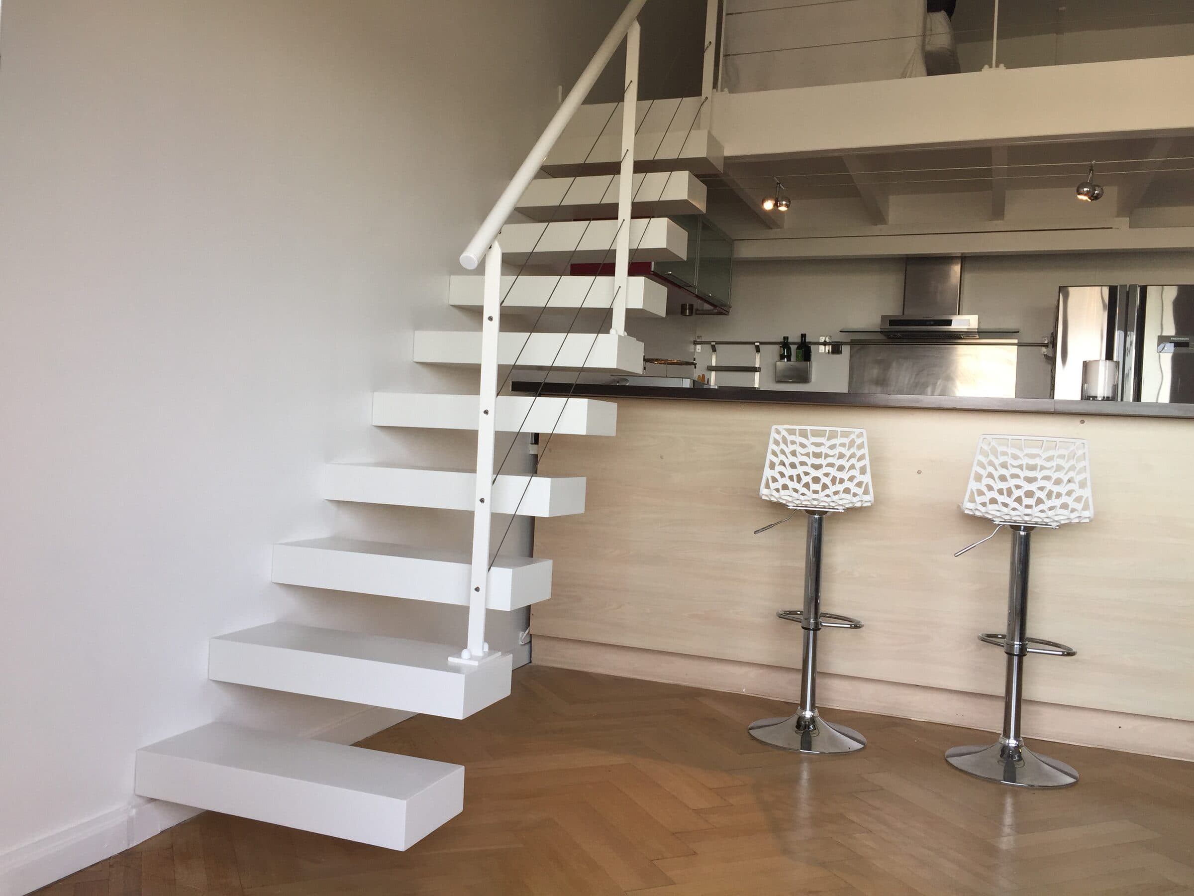 Escalier suspendu blanc et cuisine ouverte, espace lumineux